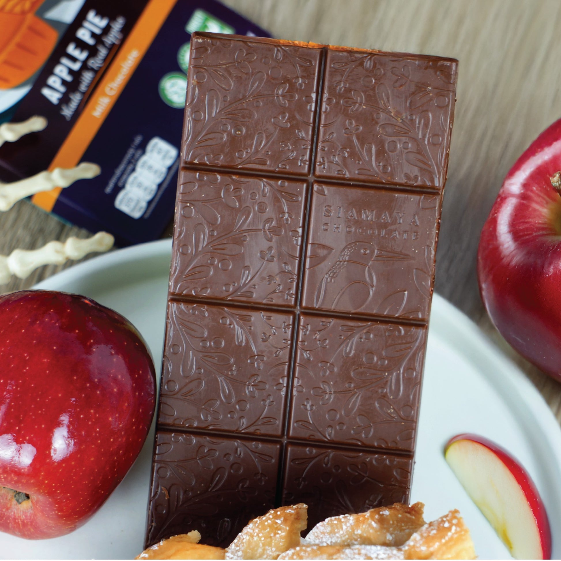 Chocolate bar with embossed design on a plate with apples and pastries