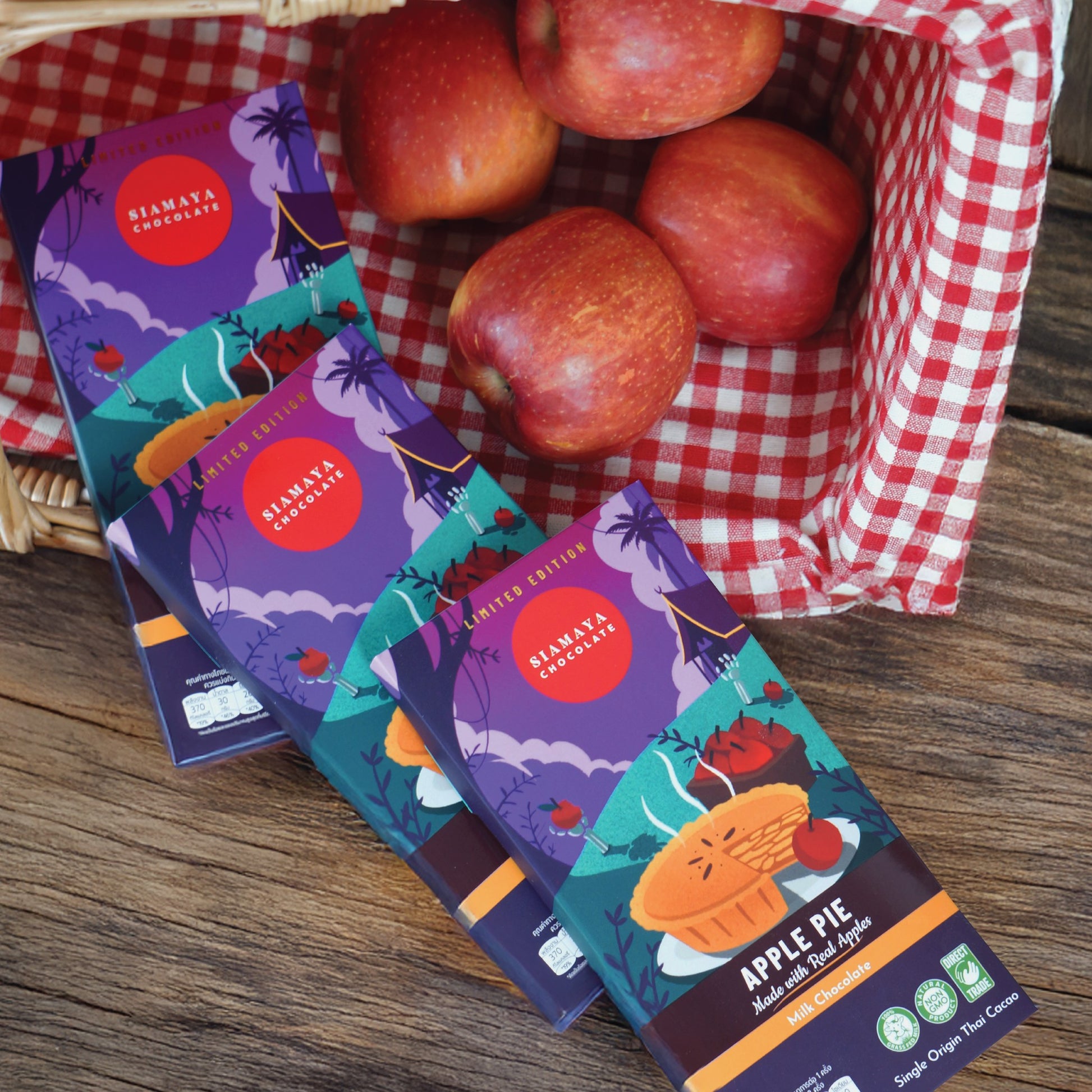 Bismaya Chocolates Apple Pie chocolate bars with a basket of apples on a checkered cloth.
