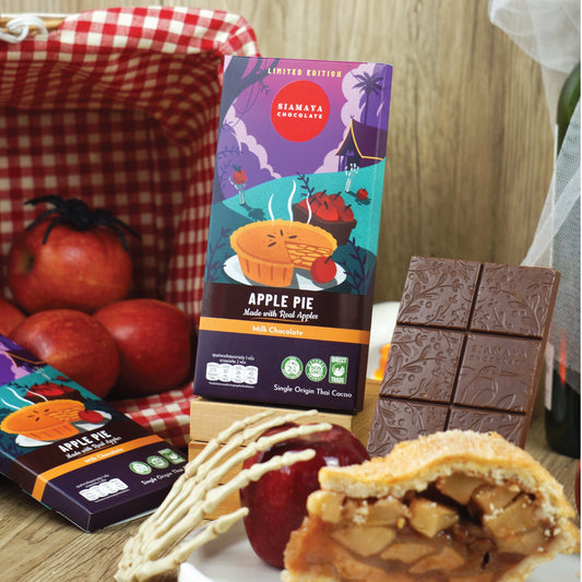 Apple pie chocolate bar packaging with a slice of apple pie and apples on a wooden table.