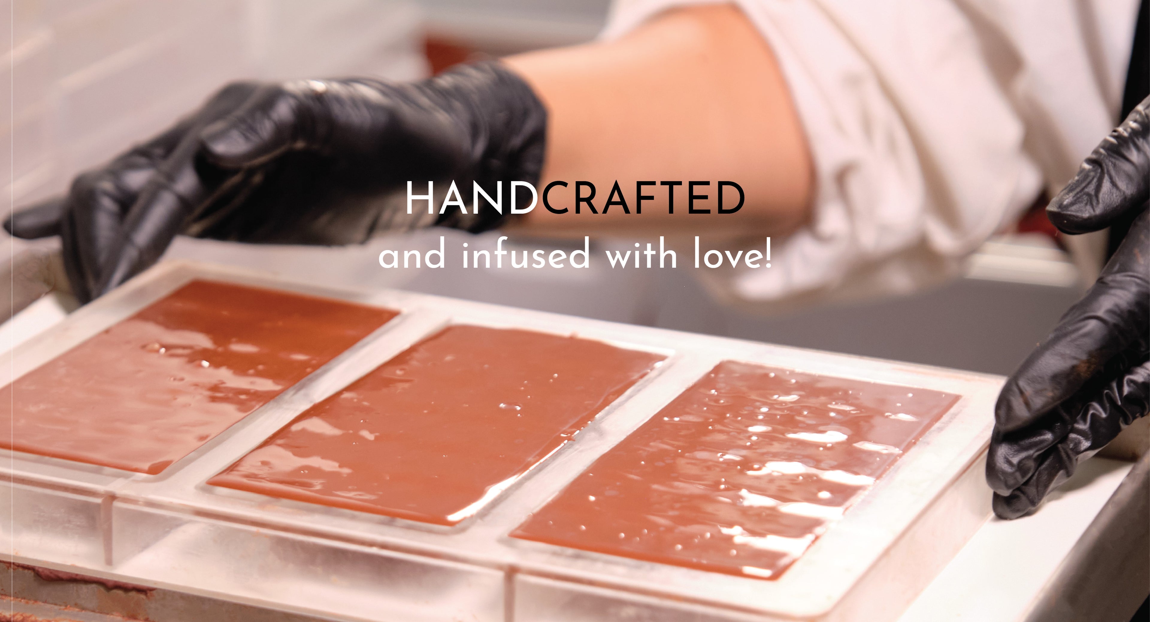 Chocolatier making handcrafted chocolate bar in mold with handcrafted and infused with love text.