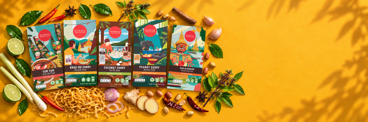 Five Siamaya Thai curry chocolate bars with herbs, spices, peanuts and chilies on a golden yellow background.